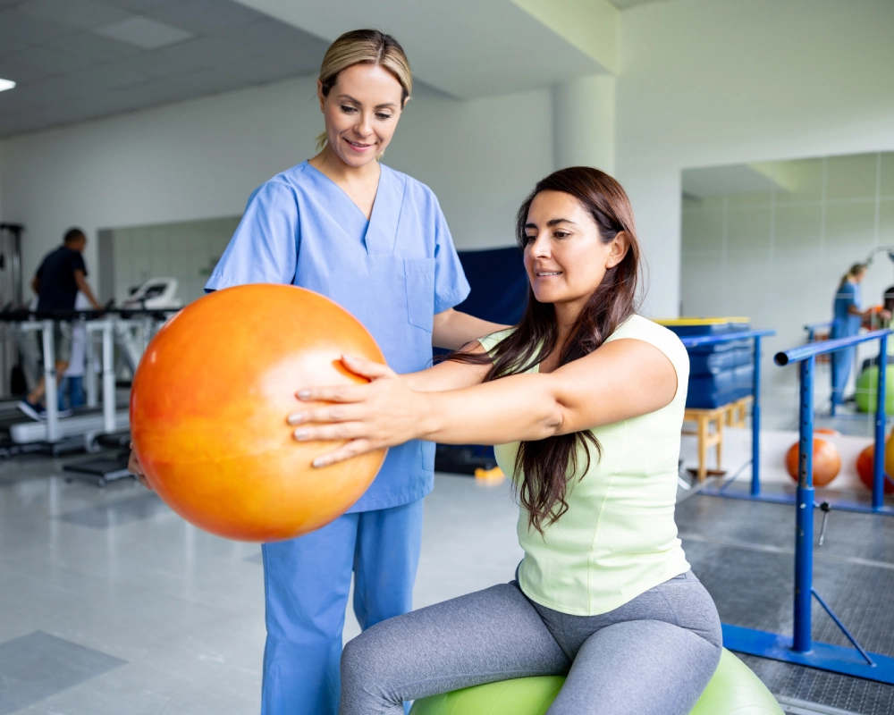Woman exercising with therapist and stability ball.