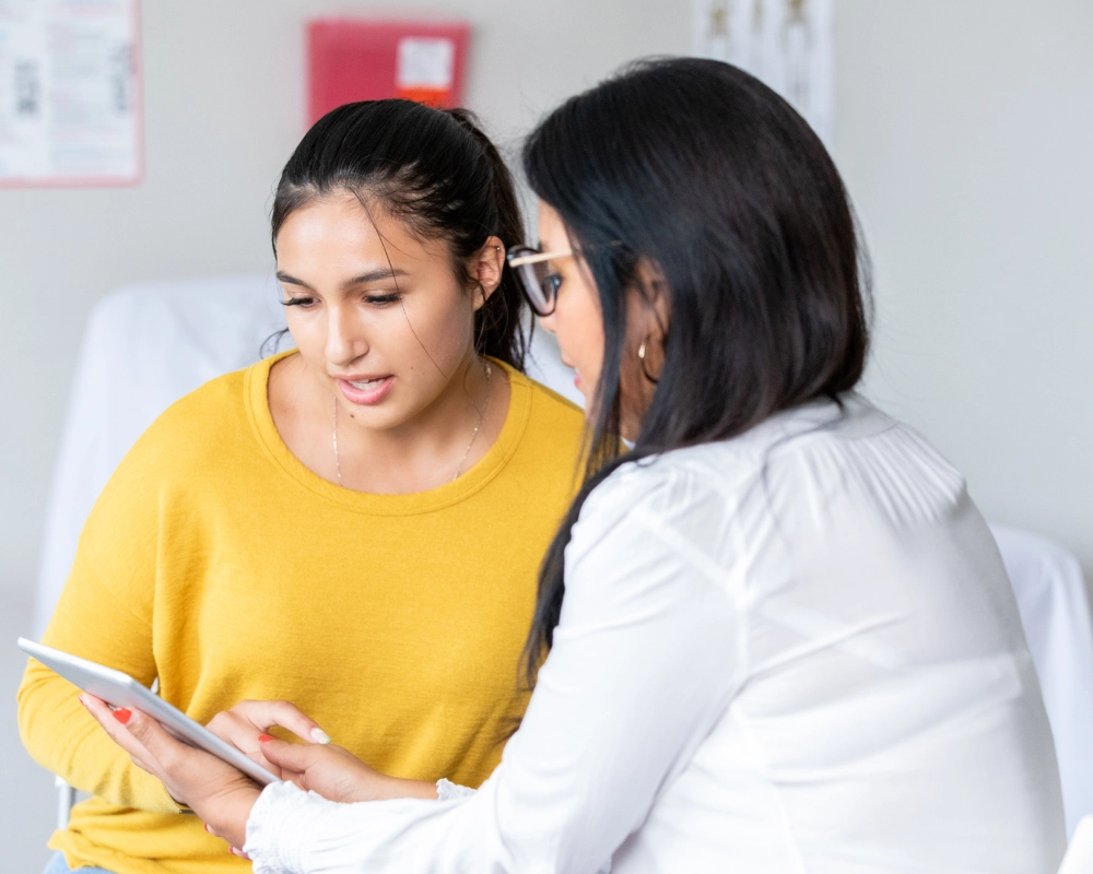 Two women discussing information on a tablet.