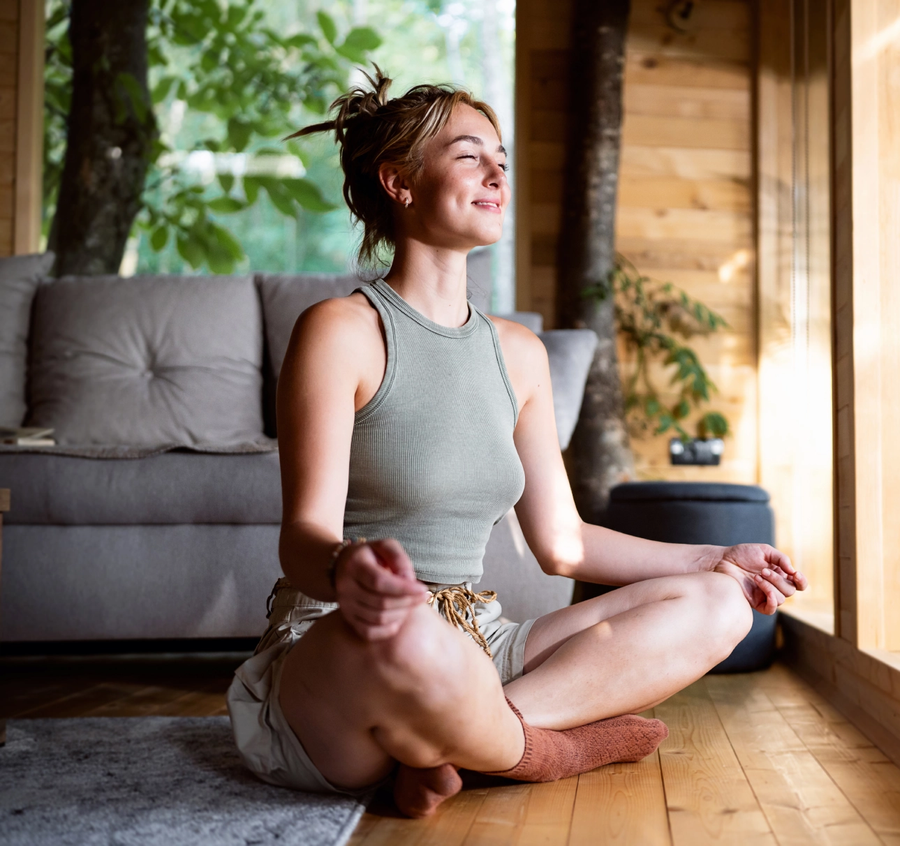 Woman meditating in a cozy wooden room.