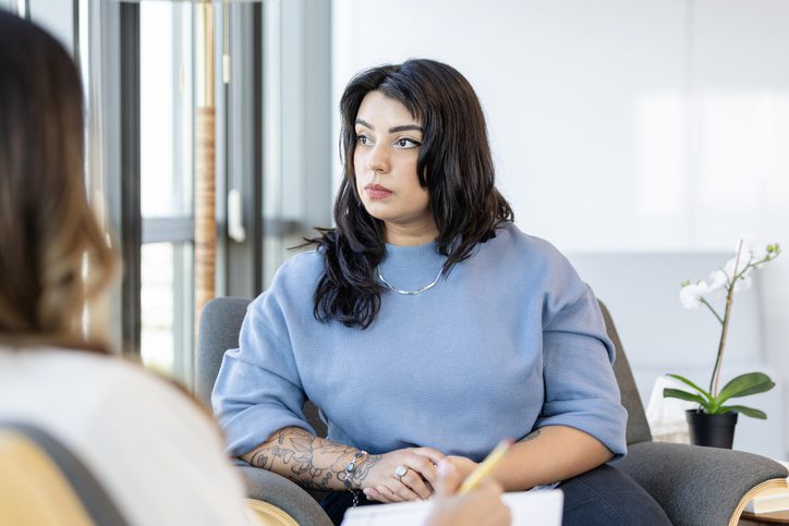 While an unrecognizable therapist gives advice, a young woman looks away.